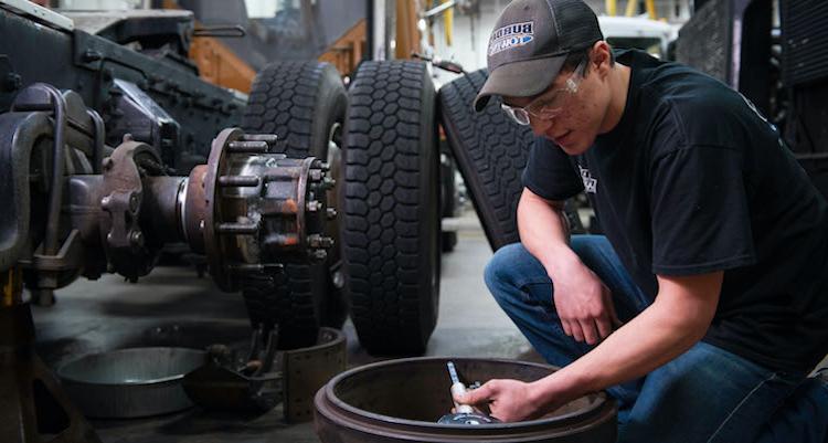 一名男子在车库里修理一个大卡车轮胎