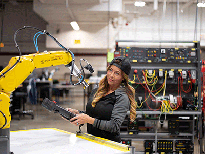 female robotics student controls robotic arm with remote